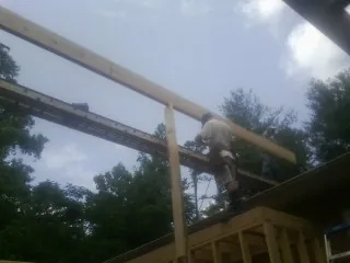 Carpenter setting a ridge beam over a new addition frame — Ice Dam Removal by Roofing Brothers in Saltville