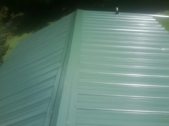 New green metal panels meeting at the ridge of a roof — Flat Roof Repair work by our crew in Saltville
