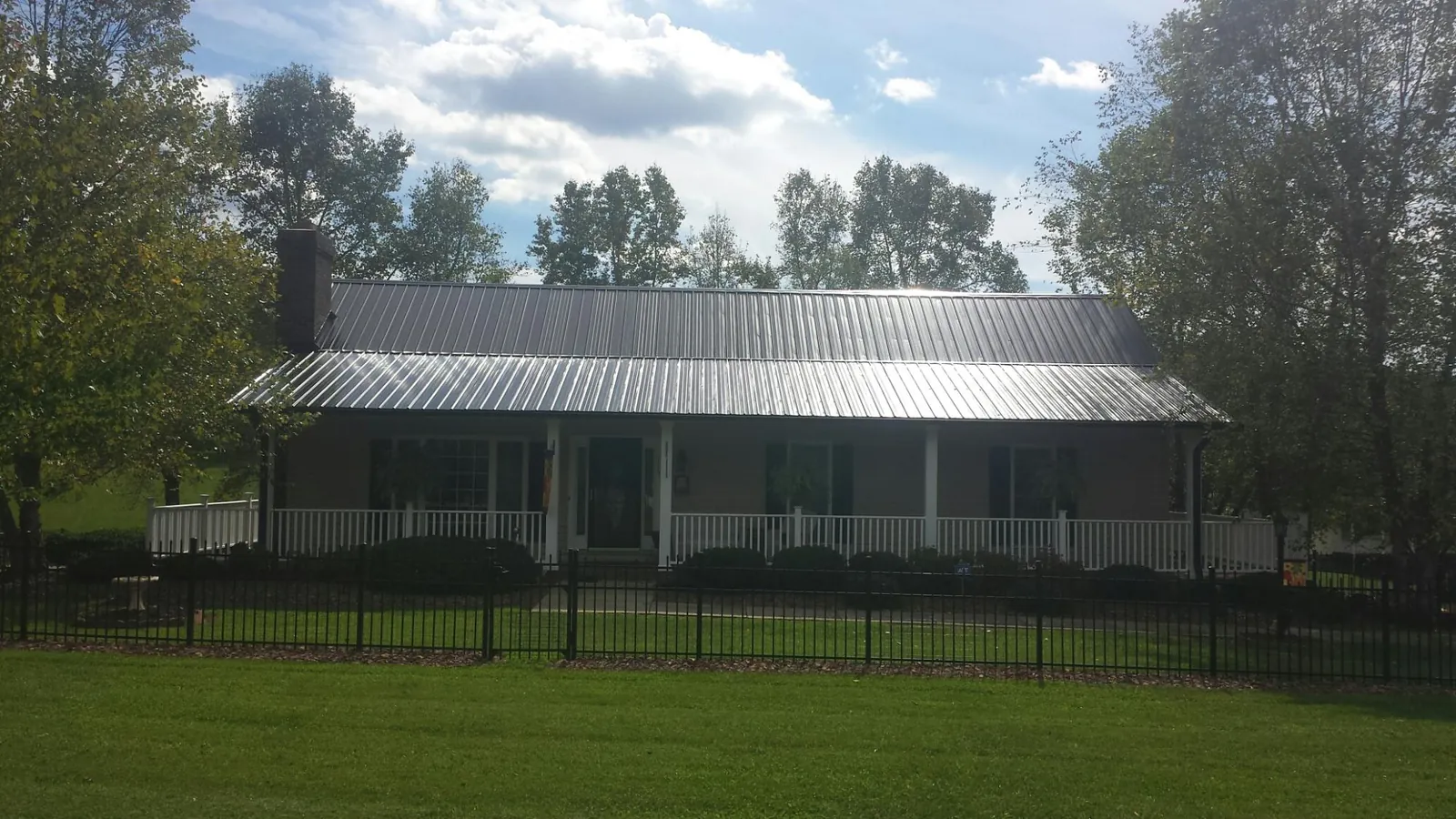 Gray metal roof on a brick ranch with a full width front porch — Gutter Guard Installation work by our crew in Saltville