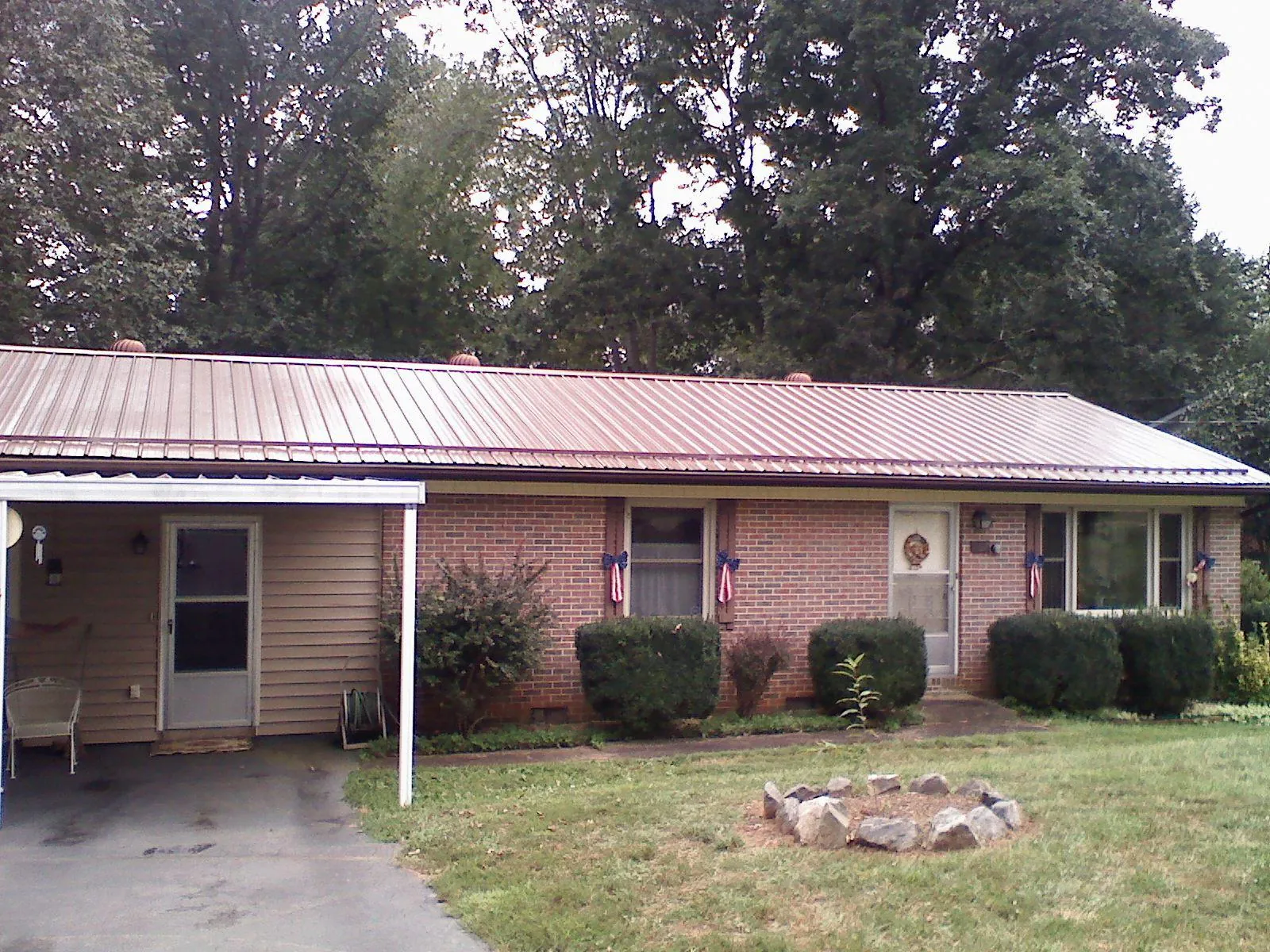 Bronze metal roof and carport on a brick ranch home — Roof Repair work by our crew in Saltville