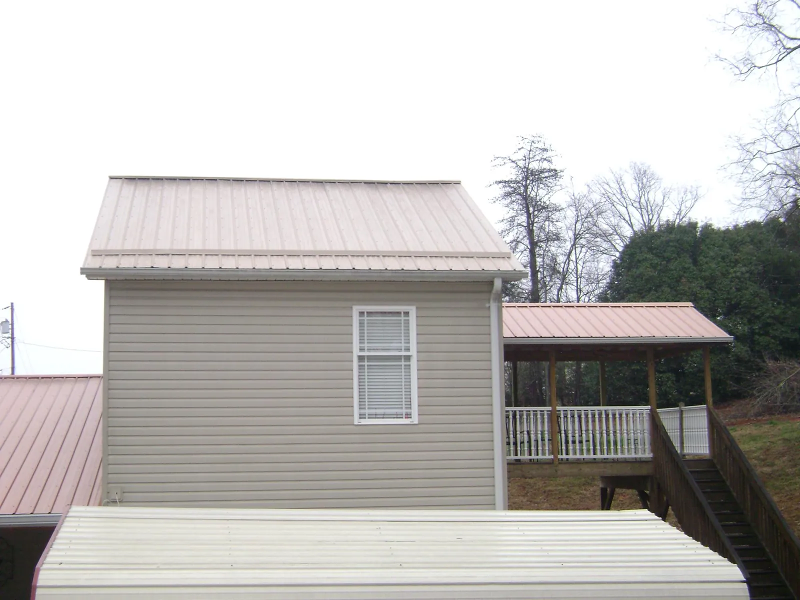 Tan metal roofs on a two story addition and attached porch, from a Roof Replacement job in Saltville