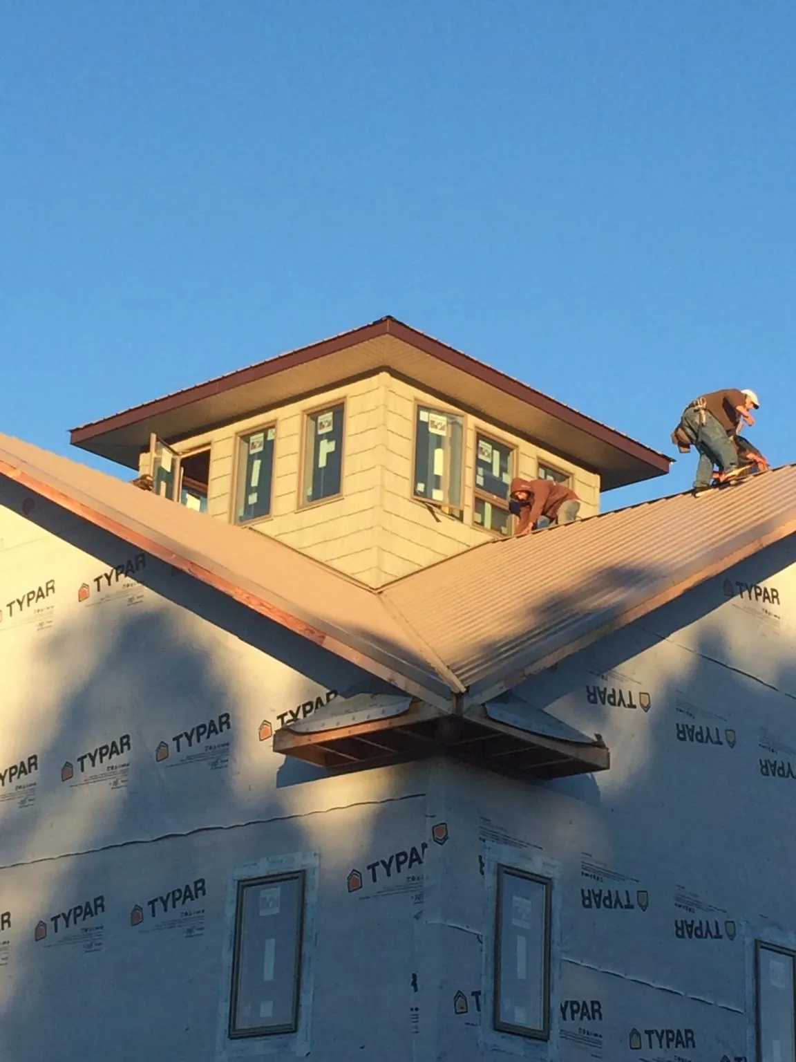 Roofers working around a rooftop cupola on a new metal roof at sunset — Roof Waterproofing in Saltville by Roofing Brothers